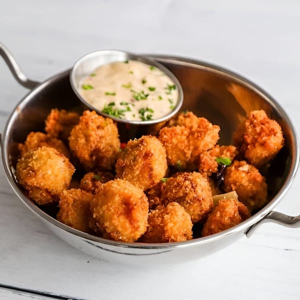 RJ Gator's fried mushrooms, golden brown and crispy, served in a metal pan with a side of dipping sauce.