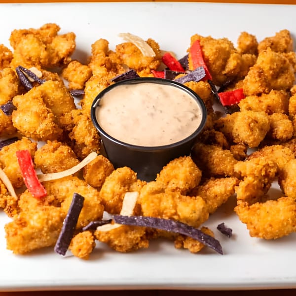 RJ Gator's fried gator tail appetizer with dipping sauce and colorful tortilla strips.